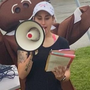 Photo of Anna, organizer announcing the beginning of the race with man in gingerbread costume excitedly waving his arms behind her