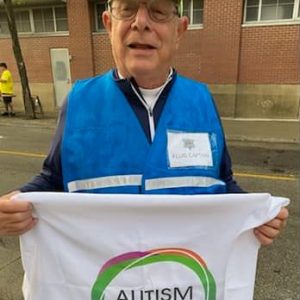Norm, Marathon Fluid Captain older man holding Autism Connection flag