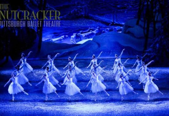 Photo of ballet dancers on a softly blue lit stage in mid dance of the Nutcracker