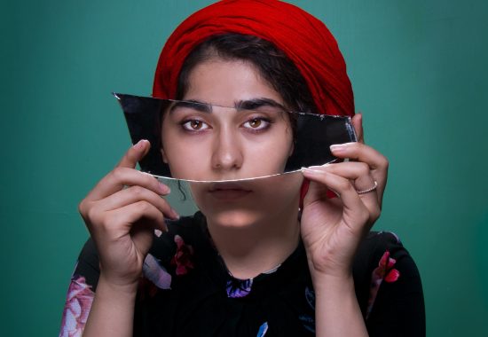 Woman facing camera holding a mirror that reflects her eyes back into the camera