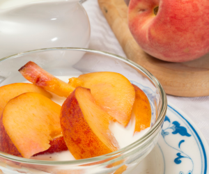 peaches cut up into a bowl of cream