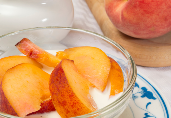 peaches cut up into a bowl of cream