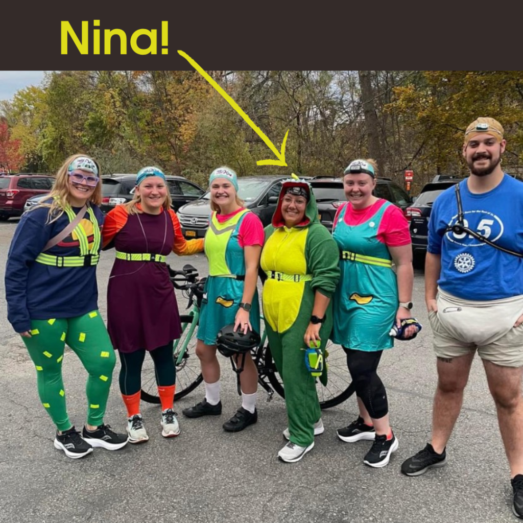 Nina dressed as a dinosaur standing with fellow runners wearing costumes