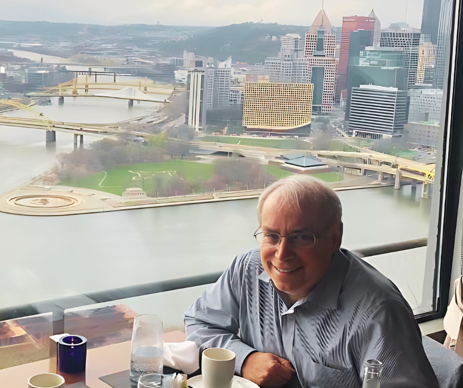 Dr Faber sitting in front of large window overlooking Pittsburgh Point