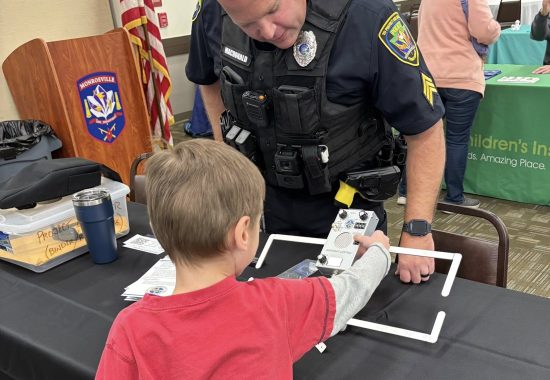 police officer demonstrating Project Lifesaver to a child